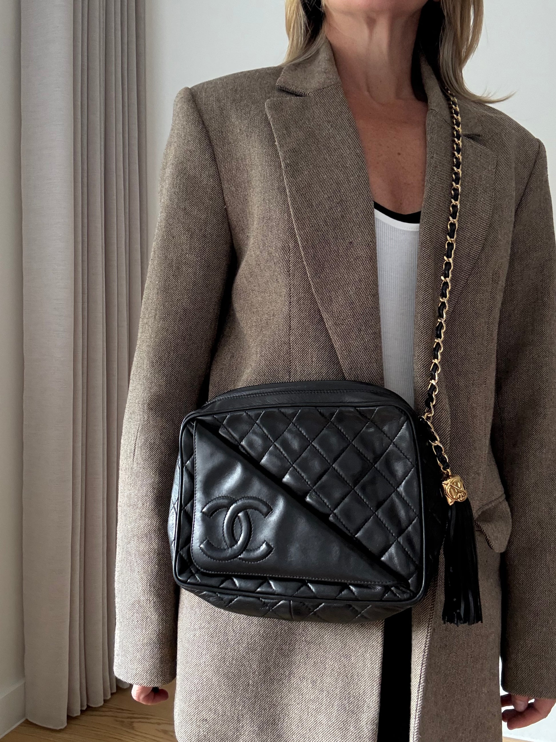 Vintage Chanel black quilted lambskin tassel camera bag front view with gold chain on model