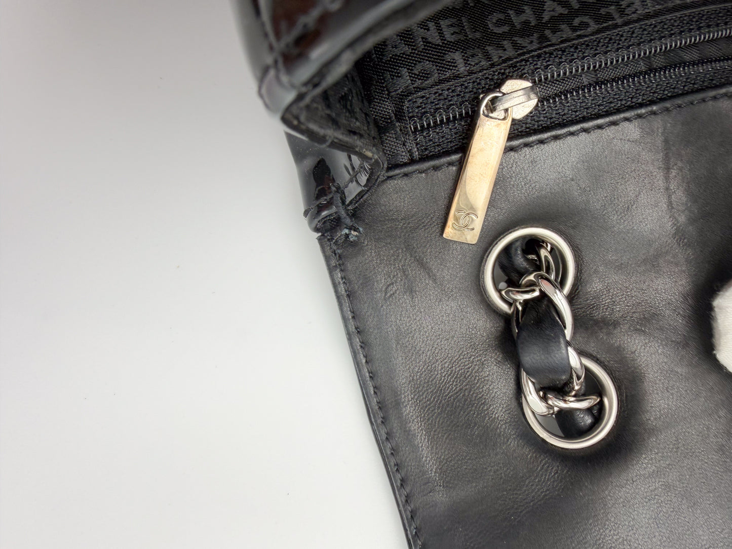 Vintage Chanel flap bag zipper pull branding and leather interior detail, silver hardware