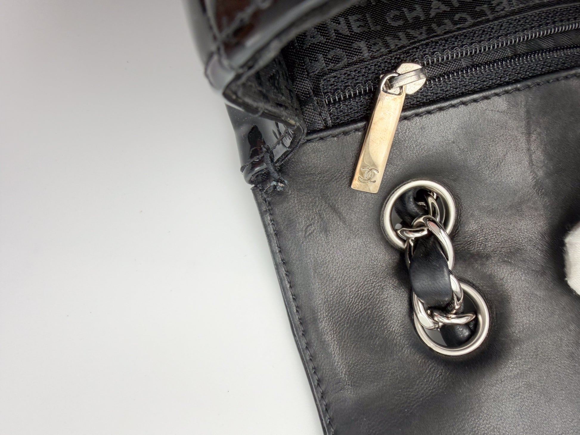 Vintage Chanel flap bag zipper pull branding and leather interior detail, silver hardware