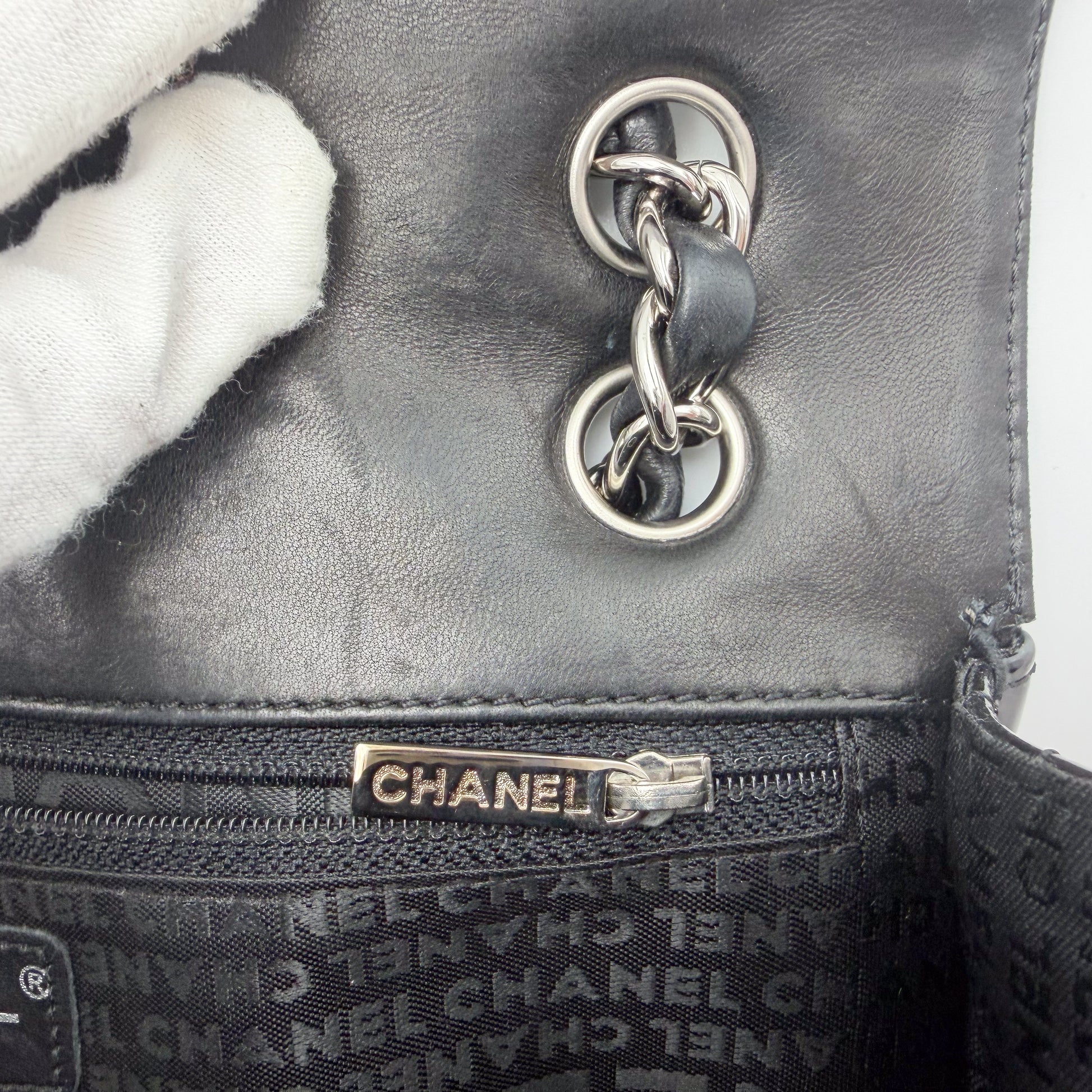 Vintage Chanel flap bag zipper pull branding and leather interior detail, silver hardware