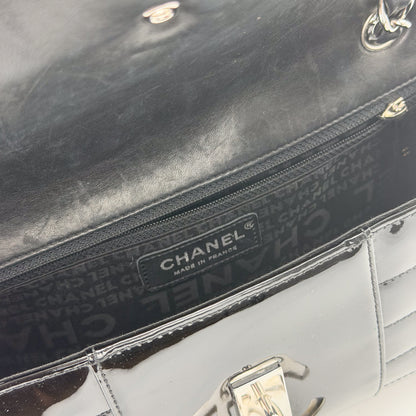 Interior view of Chanel vertical stitch patent flap bag showing printed lining, zip pocket and turnlock mechanism