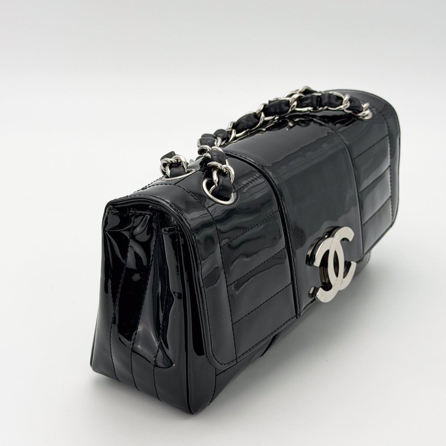 Chanel vertical stitch black patent flap bag, silver hardware, three-quarter side angle