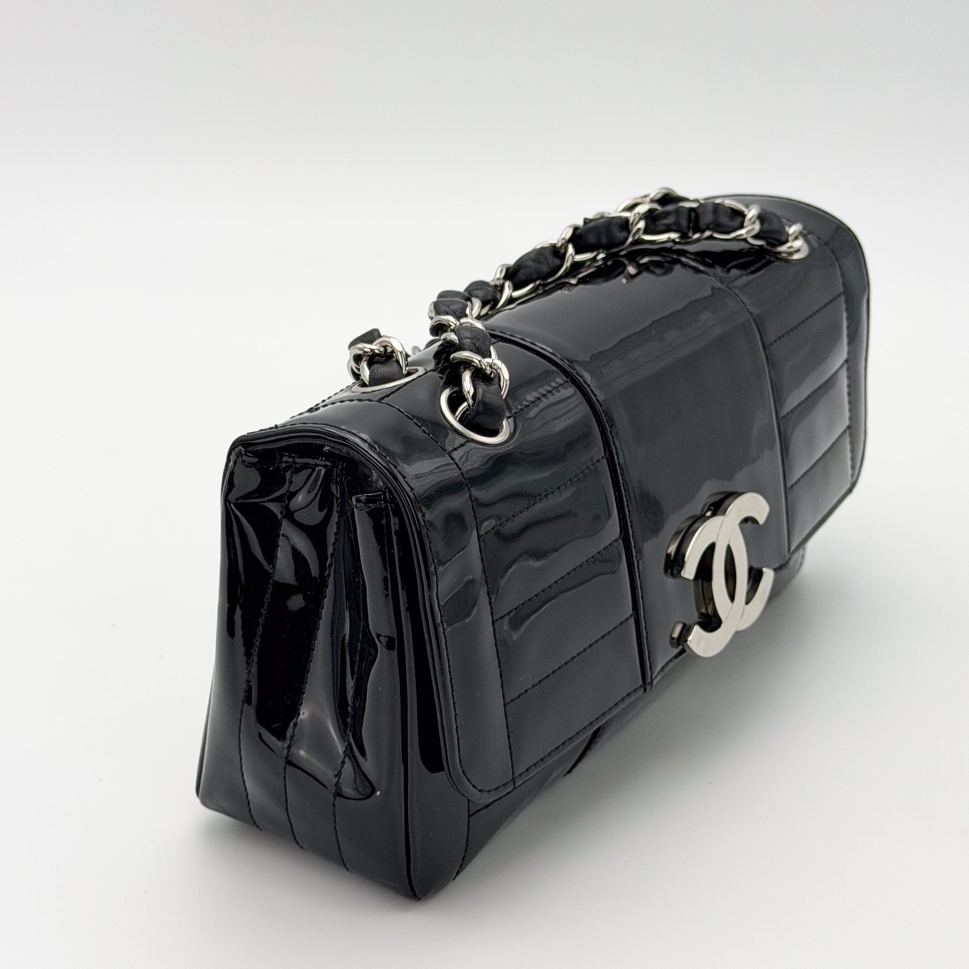 Chanel vertical stitch black patent flap bag, silver hardware, three-quarter side angle