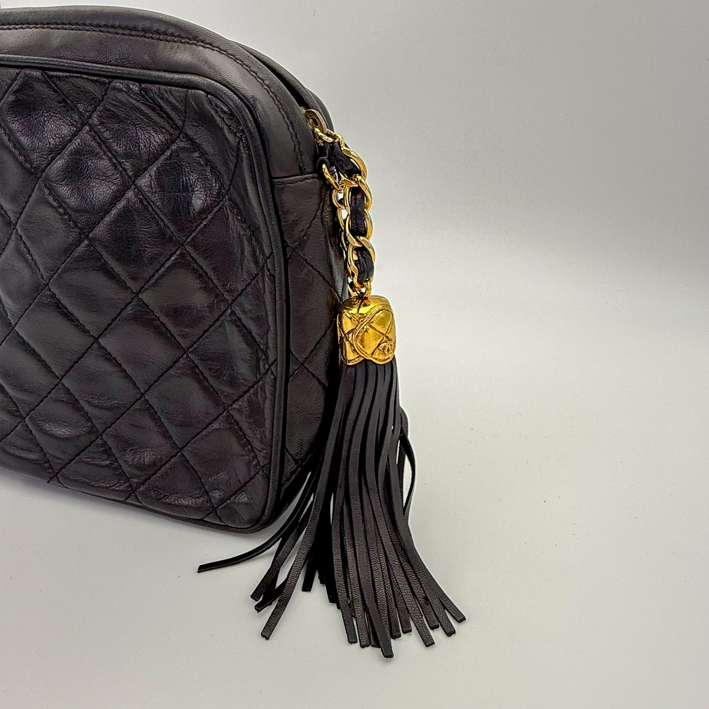 Vintage Chanel black quilted lambskin tassel camera bag with focus on the gold hardware and tassle