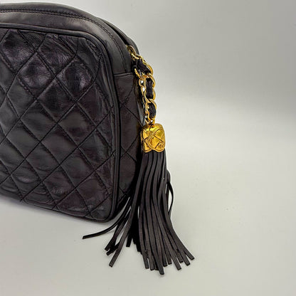 Vintage Chanel black quilted lambskin tassel camera bag with focus on the gold hardware and tassle