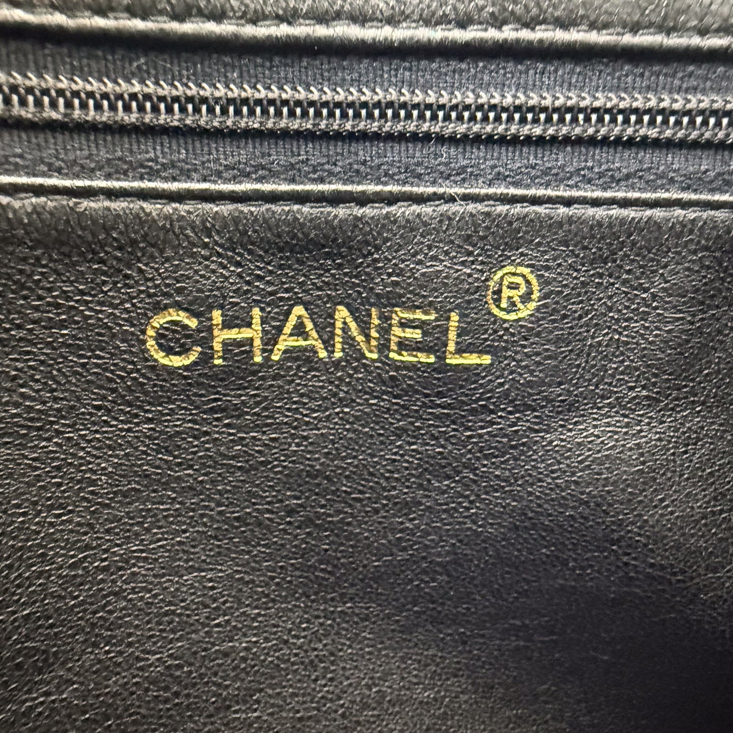 Interior view of a preloved Chanel black quilted lambskin tassel camera bag with the gold interior Chanel stamp