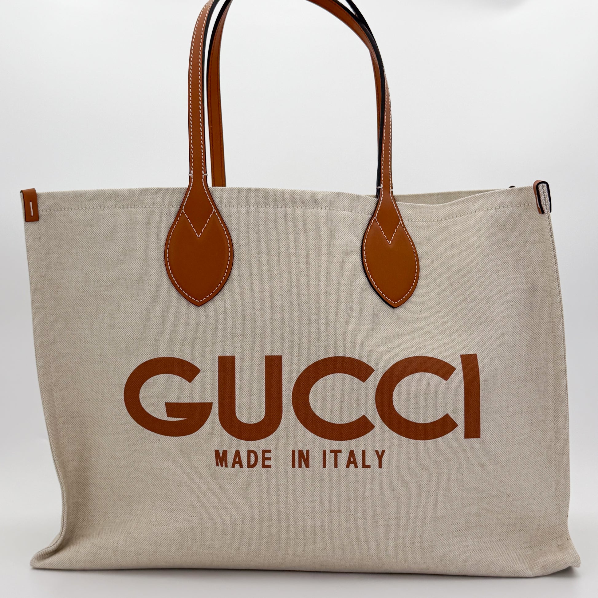 Brand new unworn Gucci logo print canvas tote front view with tan leather trim and GUCCI logo