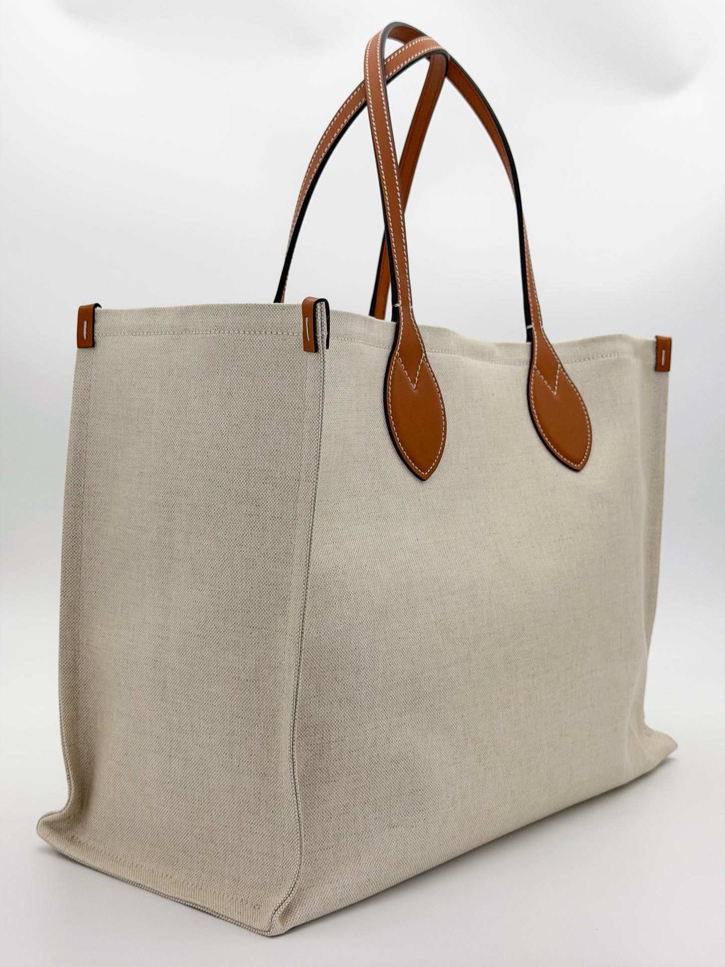 Brand new Gucci canvas tote side view showing natural canvas and leather handles