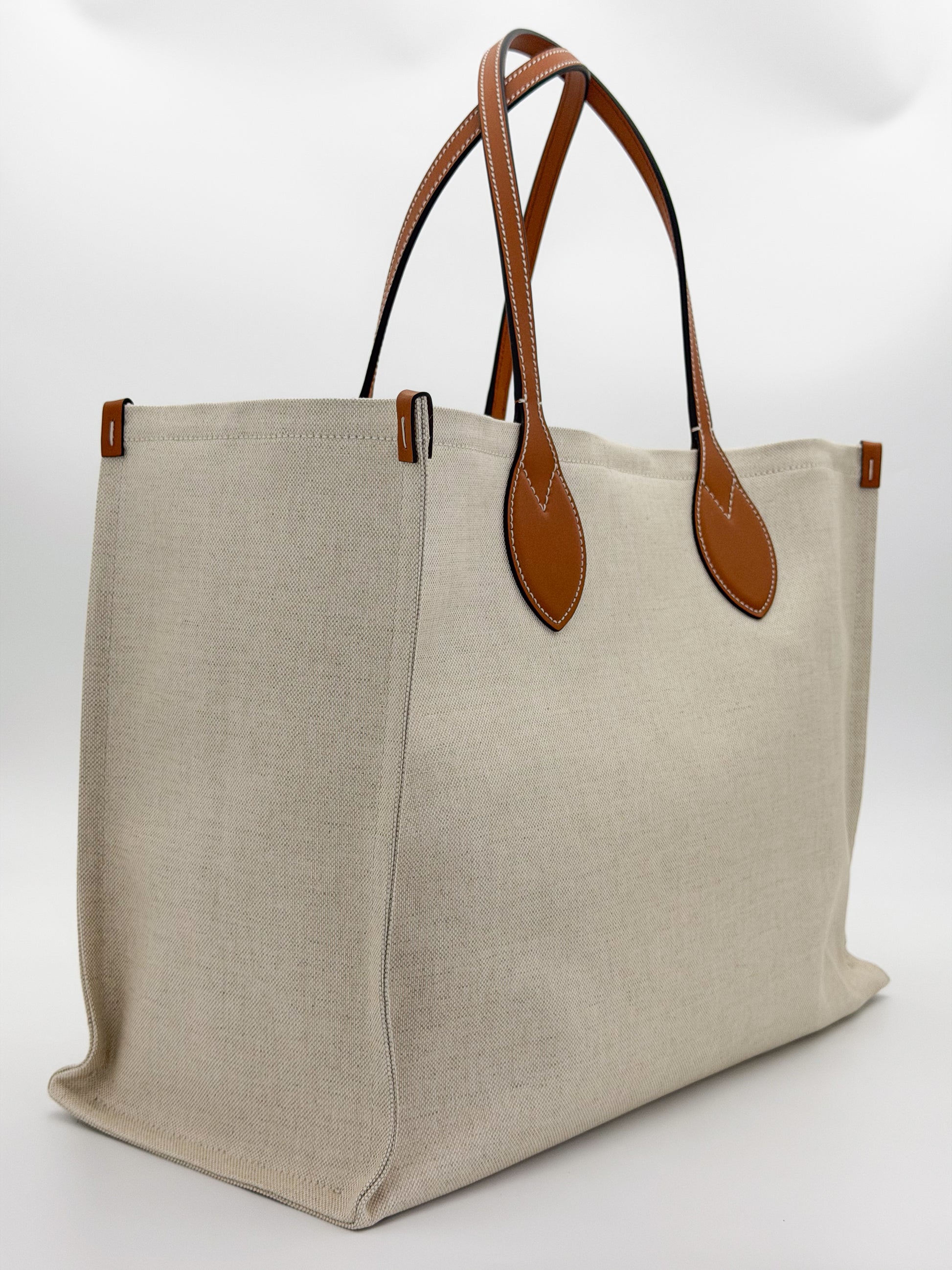 Brand new Gucci canvas tote side view showing natural canvas and leather handles