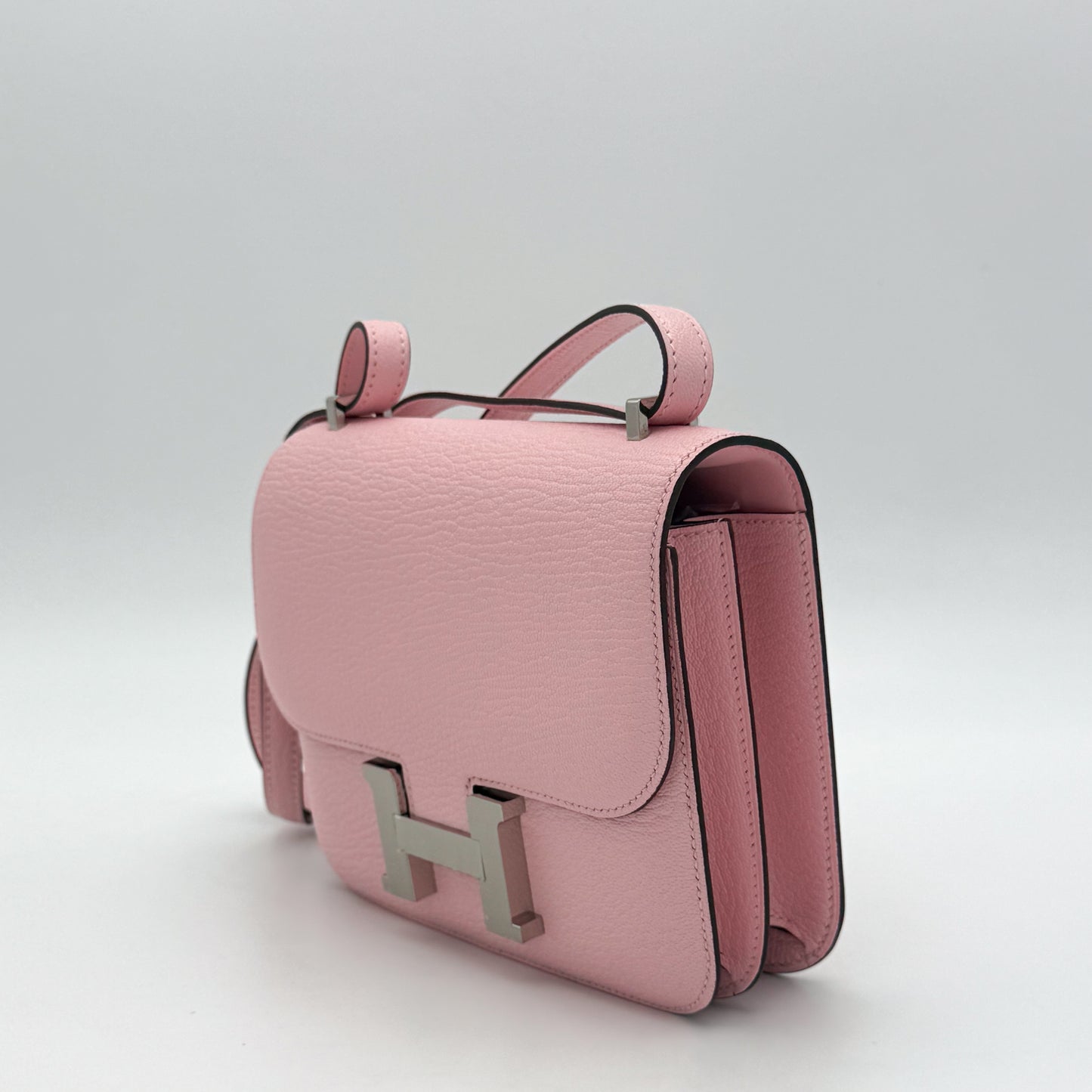 Hermès Constance 18 Rose Sakura Chèvre Mysore with original orange Hermès box and dust bag —  left side view.