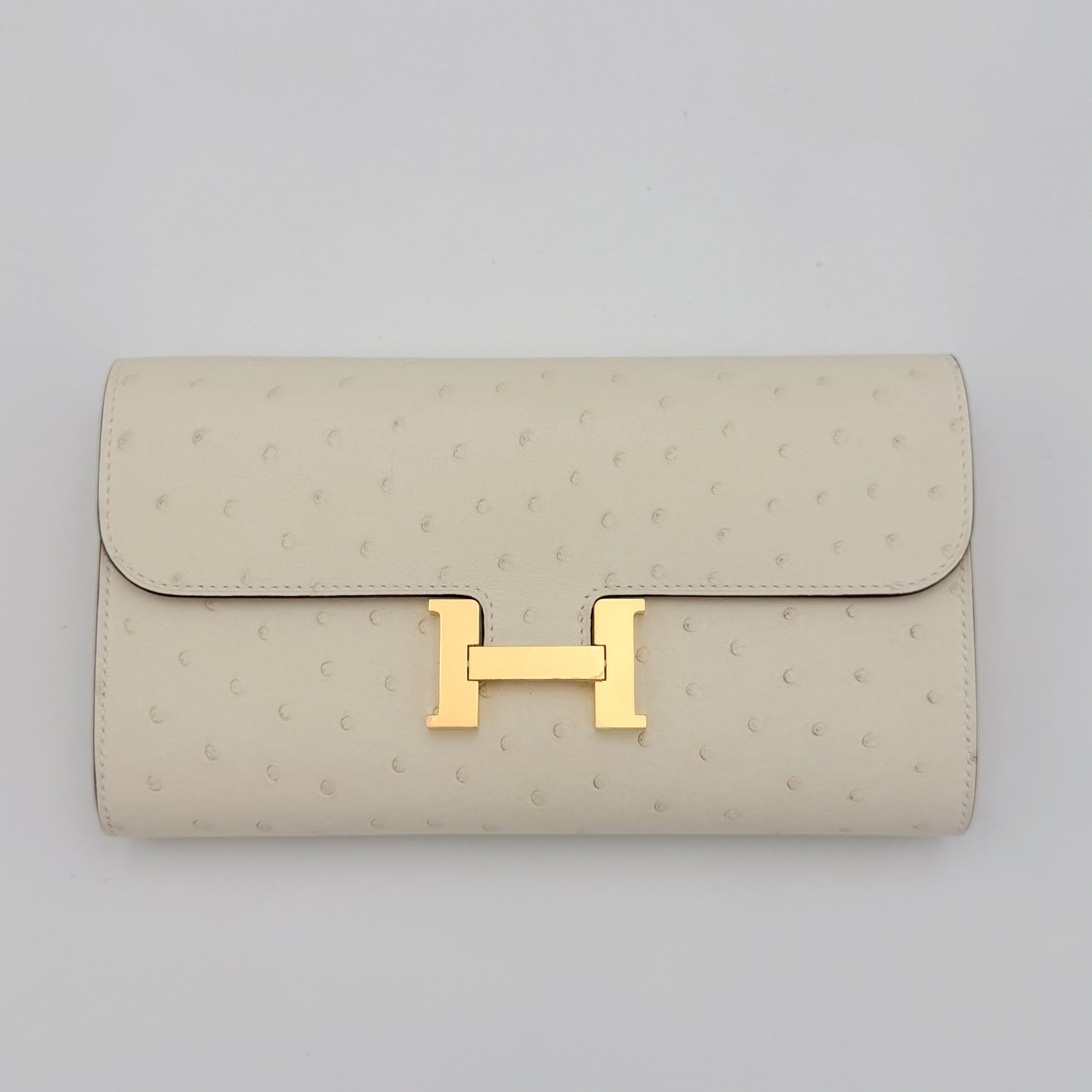 Front flat view of a brand new Hermès Constance To Go in Nata ostrich with gold hardware 
