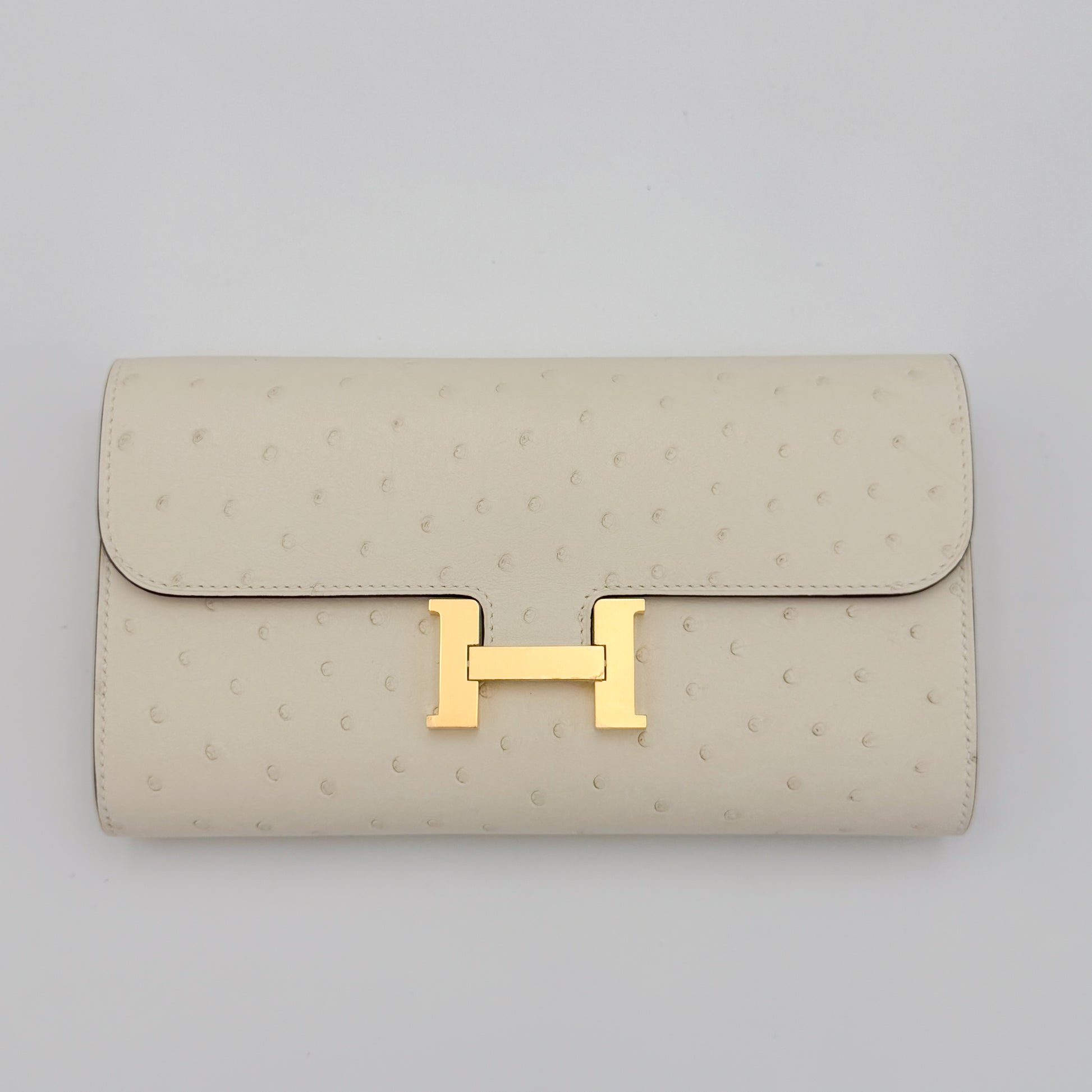 Front flat view of a brand new Hermès Constance To Go in Nata ostrich with gold hardware 
