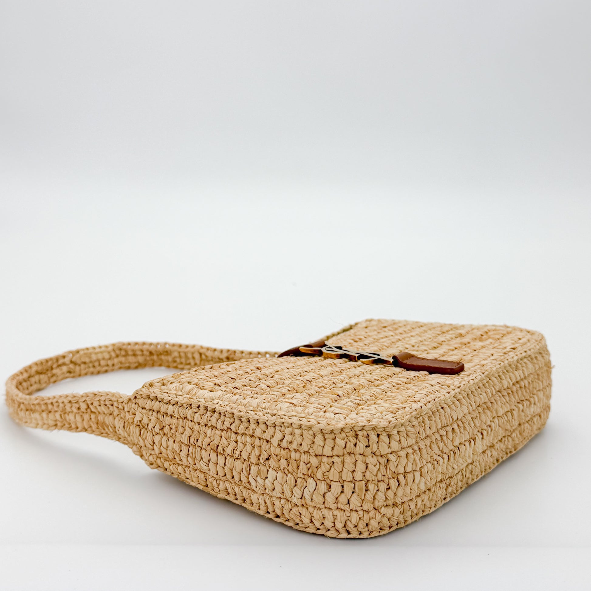Saint Laurent raffia hobo bag angled side view showing tan leather strap detail