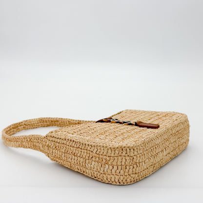 Saint Laurent raffia hobo bag angled side view showing tan leather strap detail