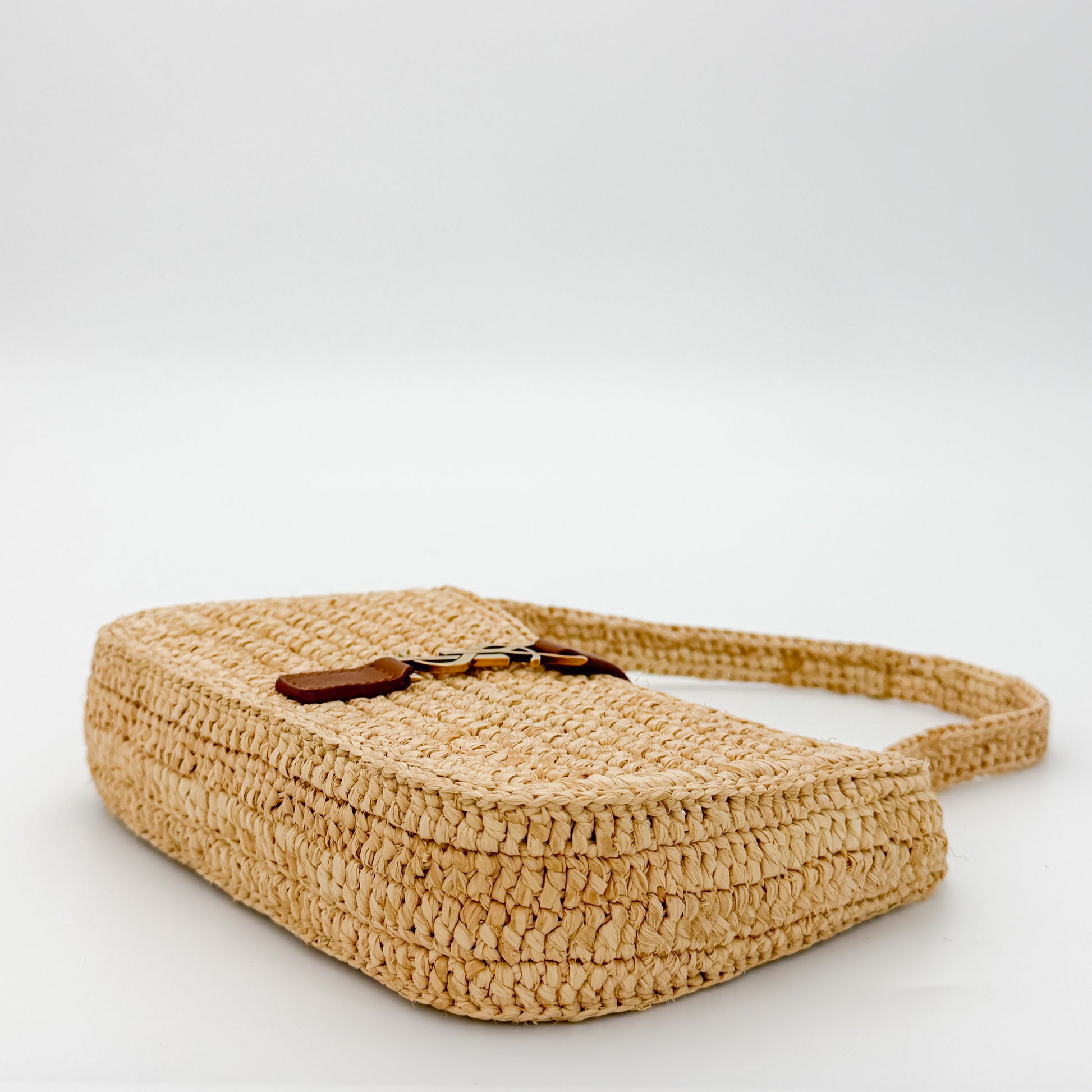 Saint Laurent raffia hobo bag angled side view showing tan leather strap detail